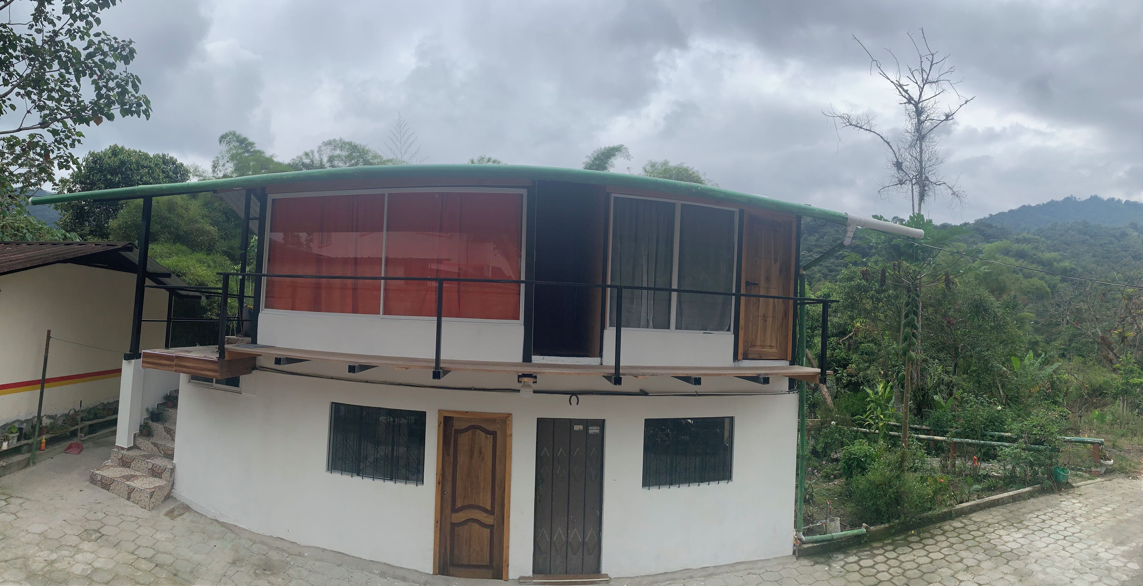 Un edificio de dos pisos con balcón, ventanas amplias y una puerta.
