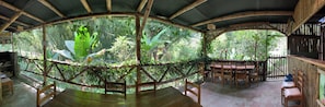 Un espace de restauration en plein air agrémenté de structures en bambou, de mobilier en bois et d’une végétation luxuriante.
