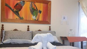 A hotel room with a bed, pillows, a painting, a wall-mounted light, and a window with curtains. - Butterfly and Bird Julio Tours-Ecolodge (Nanegal)