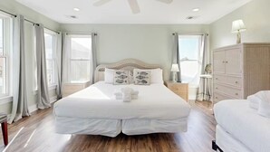 Un dormitorio amplio con una cama grande, ventilador de techo y vistas a la ciudad.