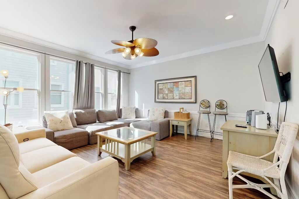 Un salon comprenant un canapé, une table basse, un téléviseur et un ventilateur de plafond.