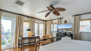 A hotel room with a bed, desk, chair, TV, and balcony view. - Award-Winning Resort Amenities | Boardwalk at Grand Pavilion 128 (Isle Of Palms)