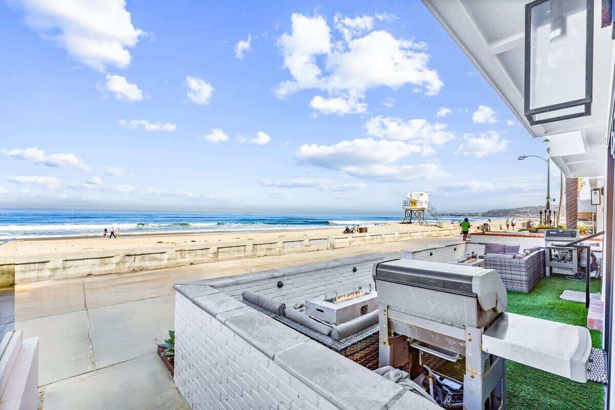 Una terraza en la azotea con vista a la playa, una torre de salvavidas y un cielo despejado.