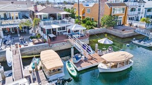Ein Yachthafen mit vertäuten Booten, einer überdachten Deckterrasse und einem Gebäude mit Balkon mit Blick aufs Wasser.