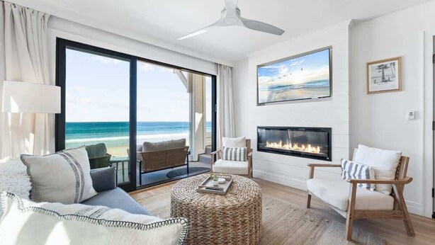 A modern living room with a large window, a fireplace, and a view of the ocean. - Luxury S Oceanfront Unit with Rooftop & Hot Tub + Sauna (San Diego)