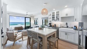 A modern kitchen with white cabinetry, a large island, and a view of the ocean. - Luxury oceanfront fourplex with roof deck, sleeps 22 (San Diego)