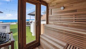 A wooden interior with a view of the ocean, a grill outside, and a clock on the wall. - Luxury oceanfront fourplex with roof deck, sleeps 22 (San Diego)