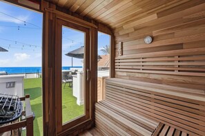 A wooden interior with a view of the ocean, a grill outside, and a clock on the wall. - Luxury oceanfront fourplex with roof deck, sleeps 22 (San Diego)