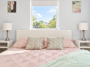 A bedroom with a bed, two nightstands, two lamps, a window with a view, and two wall art pieces. - Game Backyard + Soaking Pool - 10 Min to Brickell (Miami)
