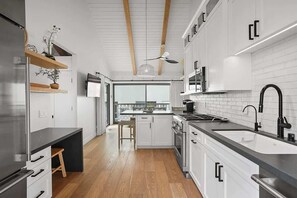 Eine moderne Küche mit weißen Schränken, einer schwarzen Arbeitsplatte und einer Holzbalkendecke.