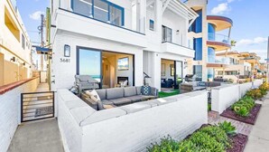 A modern multi-story residential building with a balcony, a number '3681' on the facade, and a well-maintained garden area. - Luxury Ground N Oceanfront Unit with Patio Lounge (San Diego)