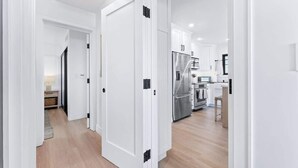 A modern kitchen with white cabinetry, a stainless steel refrigerator, and a wooden floor. - Luxury Ground N Oceanfront Unit with Patio Lounge (San Diego)