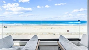 Vista da praia a partir de um quarto com duas cadeiras brancas estofadas viradas para o oceano.