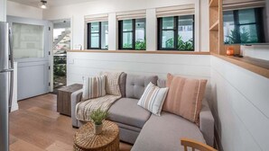 A modern living room with a sofa, a small table, and a TV mounted on the wall. - Neptune Charm  Coastal (Encinitas)