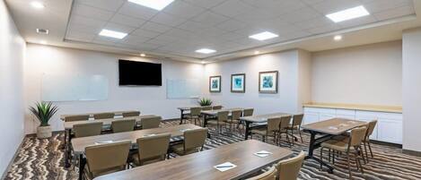 A conference room with a whiteboard, a flat-screen TV, and framed pictures on the wall.
