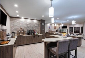 Une cuisine moderne dotée d’un îlot central, d’appareils électroménagers intégrés et de luminaires suspendus.