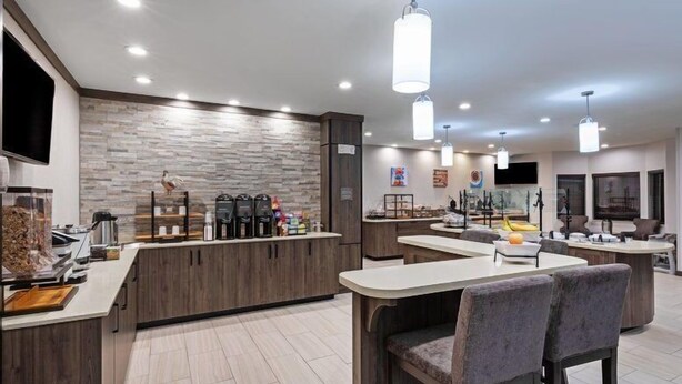 Une cuisine moderne dotée d’un îlot central, d’appareils électroménagers intégrés et de luminaires suspendus.