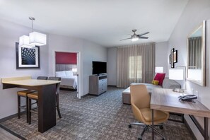 A hotel room with a bed, desk, chair, television, and a ceiling fan.