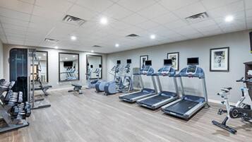 A gym with treadmills, elliptical machines, and free weights.