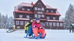 A large wooden building with the name 'JANA' on the facade, surrounded by snow-covered trees. - Hotel Bouda Jana (Pec pod Sněžkou)