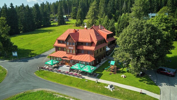 A large, two-story building with a red roof, surrounded by a well-maintained lawn and a golf course. - Hotel Bouda Jana (Pec pod Sněžkou)
