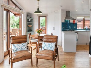 Una cocina con armarios de madera, un comedor con mesa y sillas, y vistas al exterior.