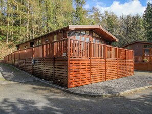 Una cabaña de madera con techo inclinado, ventanas grandes y un cerramiento exterior.