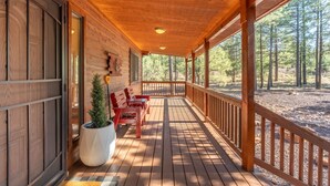 A wooden cabin with a covered porch, a small table with chairs, and a potted plant.