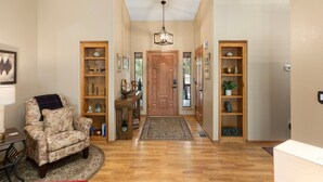 A hallway with a wooden door, a chair, and two wooden shelves with decorative items.