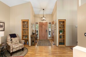A hallway with a wooden door, a chair, and two wooden shelves with decorative items. - Mountain Retreat w/ patio | Near downtown (Show Low)