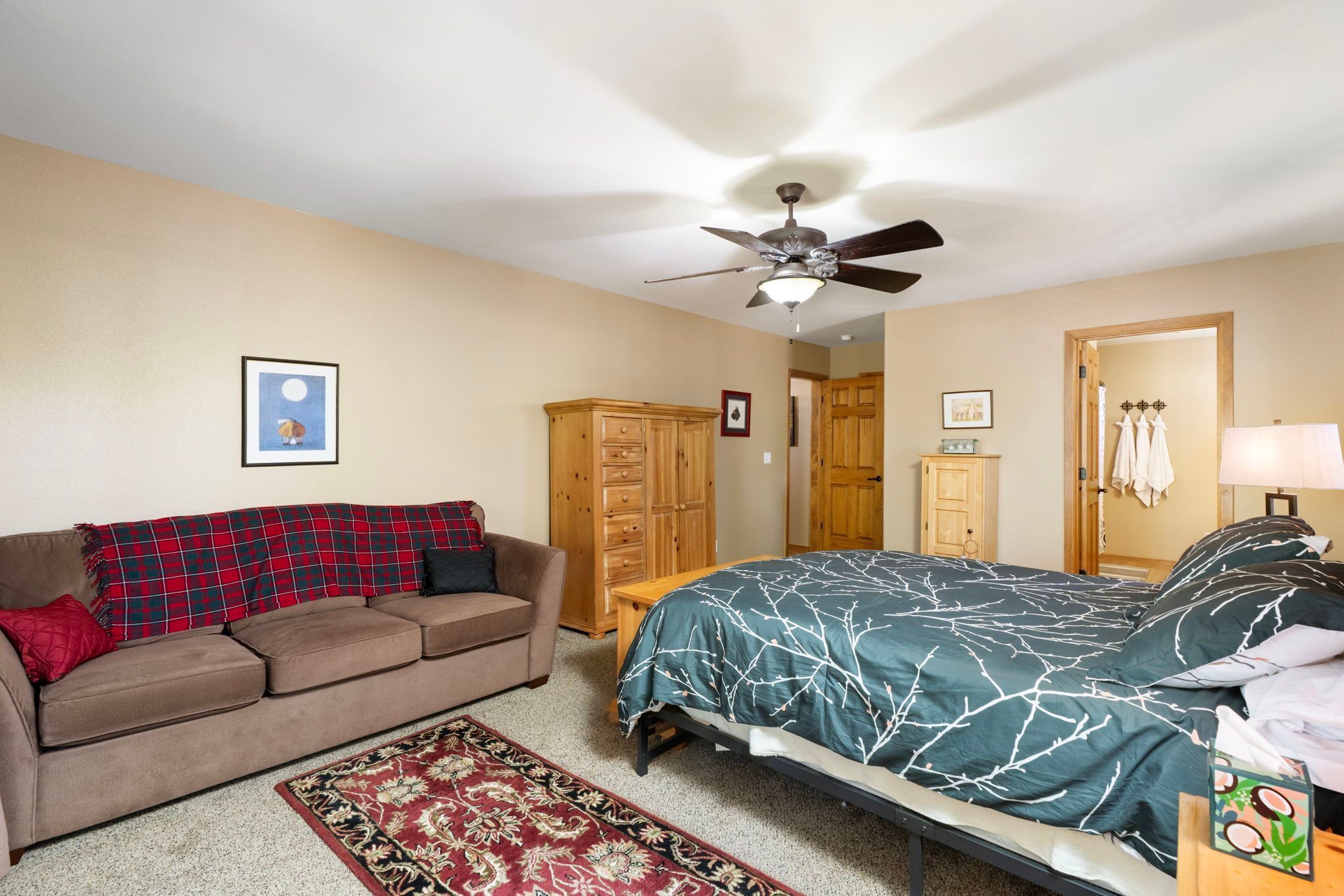Ein Schlafzimmer mit Bett, Sofa, Kleiderschrank, Deckenventilator und Teppich.