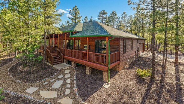 A cabin with a porch, a staircase, and a stone pathway.
