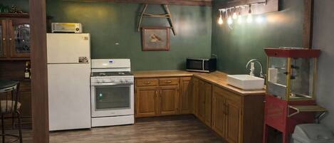 A kitchen with wooden cabinets, a white refrigerator, a stove, a microwave, and a sink.