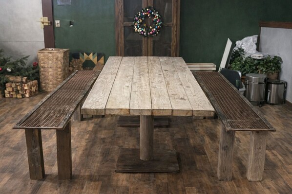 A rustic wooden table with benches, a green wall, and a wreath.