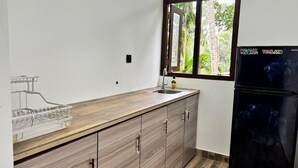 Una cucina con piano di lavoro in legno, lavello, pensili e frigorifero.