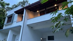 Un edificio moderno a due piani con un balcone, una porta e una piccola finestra.
