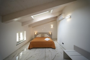 A bedroom with a bed, skylight, bedside lamps, and a window.