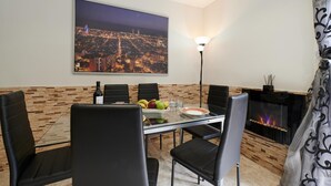 A dining area with a glass table, black chairs, a fruit bowl, a bottle of wine, and a fireplace. - Coastal Retreat at Valley View (Lloret de Mar)