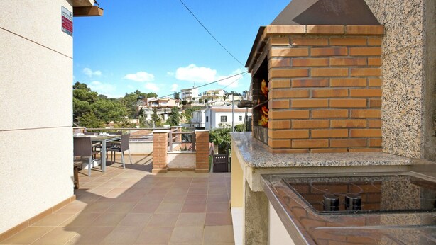 A rooftop terrace with a brick oven, tiled flooring, and a view of surrounding buildings. - Coastal Retreat at Valley View (Lloret de Mar)