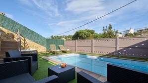 A swimming pool with surrounding wicker furniture and a stone wall. - Coastal Retreat at Valley View (Lloret de Mar)