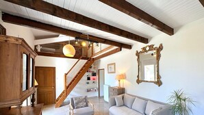 Ein geräumiger Wohnbereich mit einer Holztreppe, einem Sofa, einem Couchtisch und einem großen Spiegel.