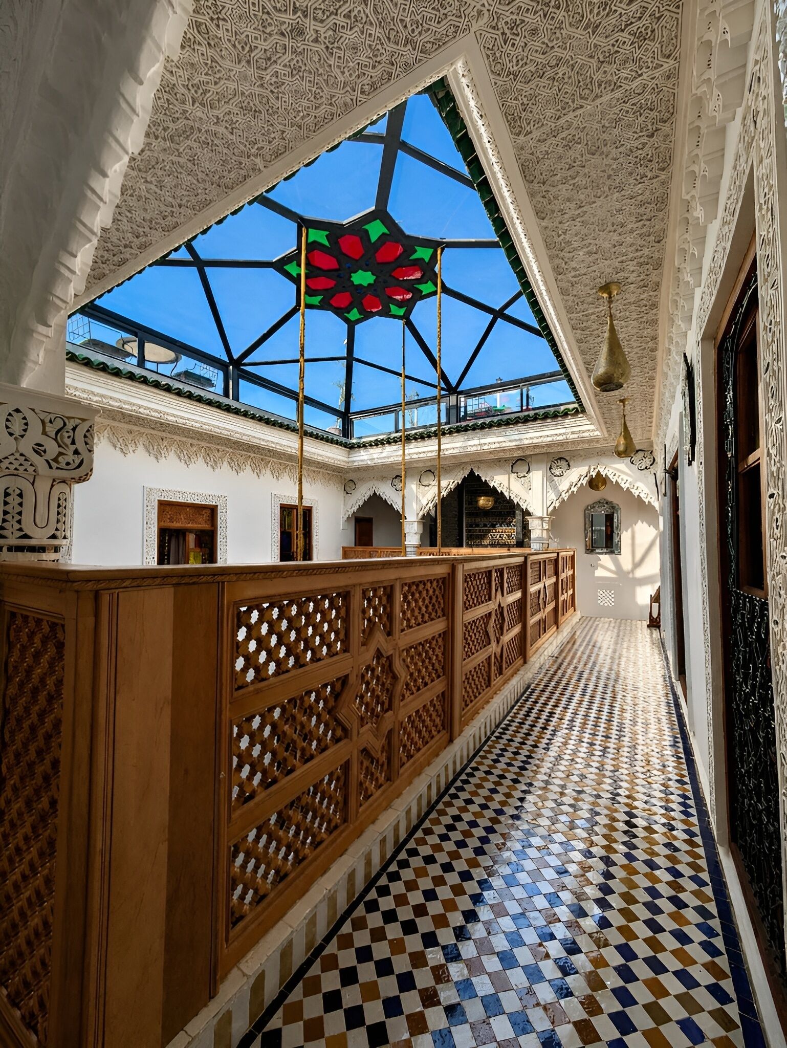 A corridor with a high ceiling, intricate wall carvings, and a patterned floor.