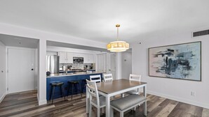 A modern kitchen with white cabinets, a blue island, and a hanging pendant light. - Bayfront Bliss in Gated Tristan Towers – 2 Bed, 2 Bath, Sleeps 4 (Pensacola Beach)