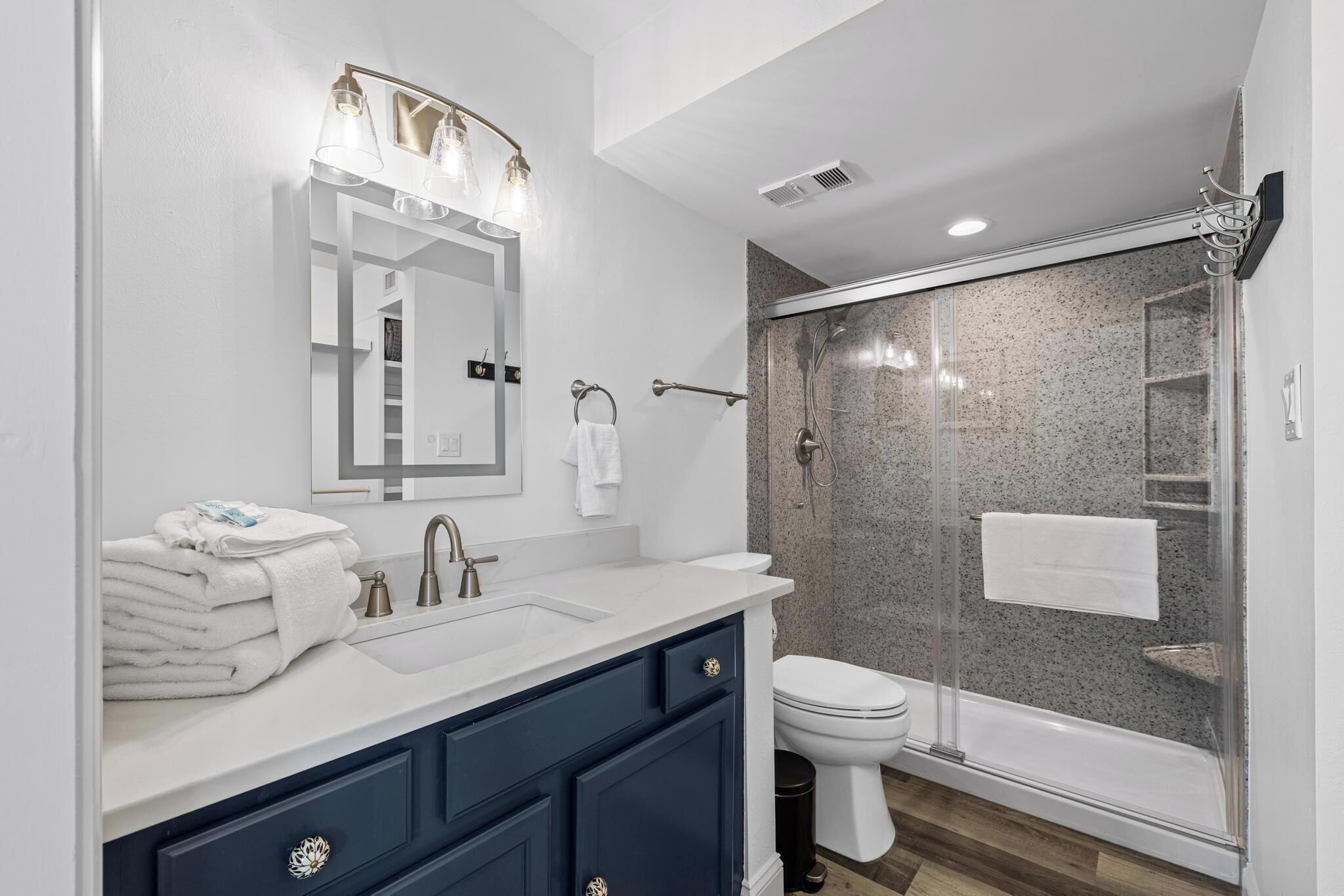A modern bathroom with a vanity, sink, mirror, and a glass shower enclosure.