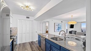 A modern kitchen with a large island, built-in appliances, and a view to the dining area. - Bayfront Bliss in Gated Tristan Towers – 2 Bed, 2 Bath, Sleeps 4 (Pensacola Beach)