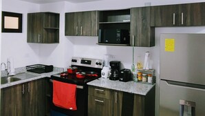 A modern kitchen with dark wooden cabinets, a stainless steel refrigerator, a microwave, a stove, and a coffee maker. - Beautiful 3 bedroom apartment, Petapolis zone 12 Guatemala (Ciudad de Guatemala)