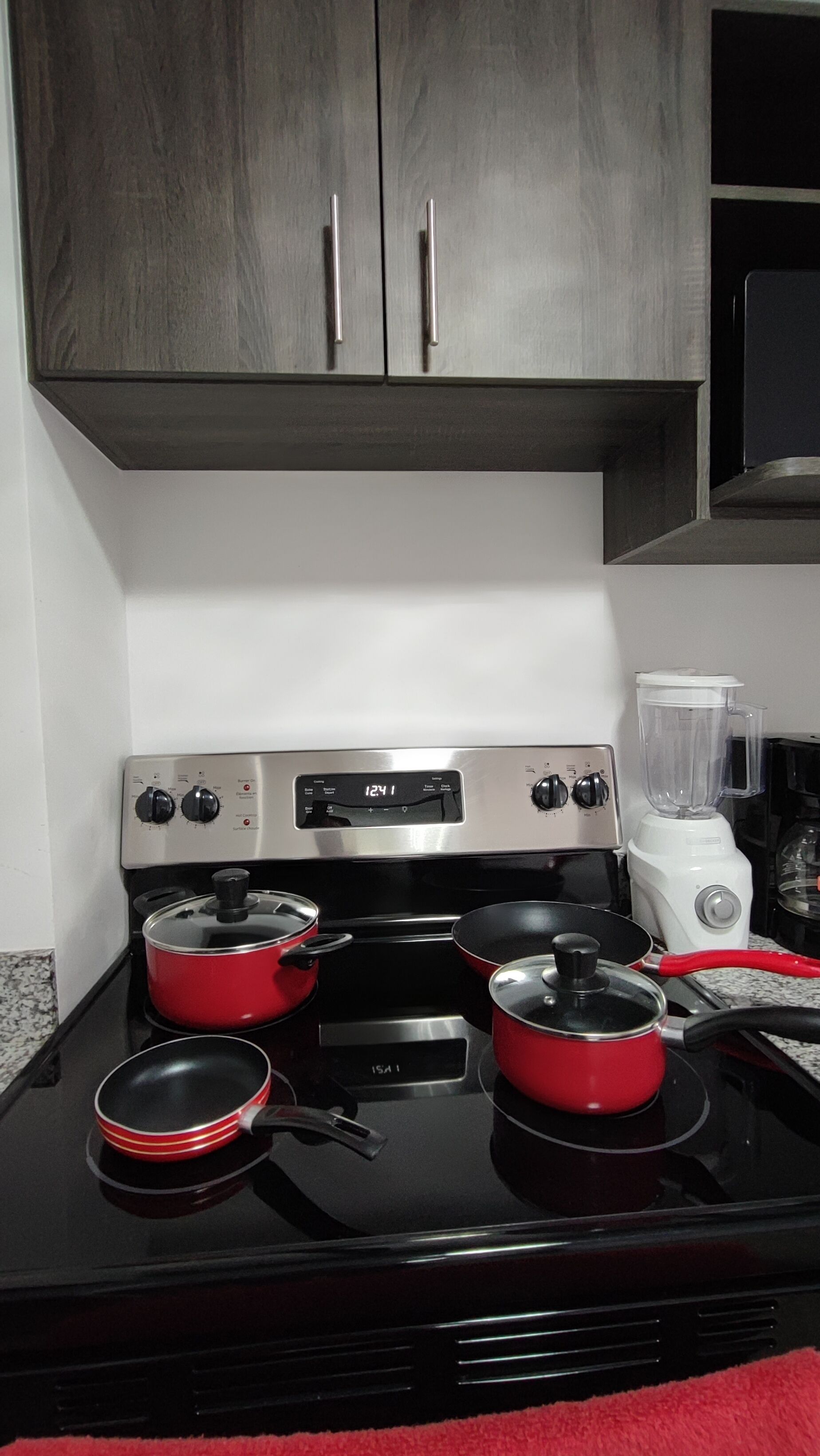 Una cocina con estufa, ollas, licuadora y armarios.