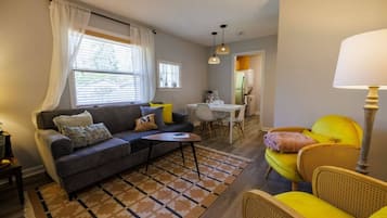 Una sala de estar con un sofá, una mesa de centro y un comedor con mesa y sillas.
