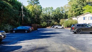 A parking lot with several cars, a fence, and a building in the background.