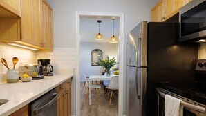 A compact kitchen with wooden cabinets, a stainless steel refrigerator, and a black oven.